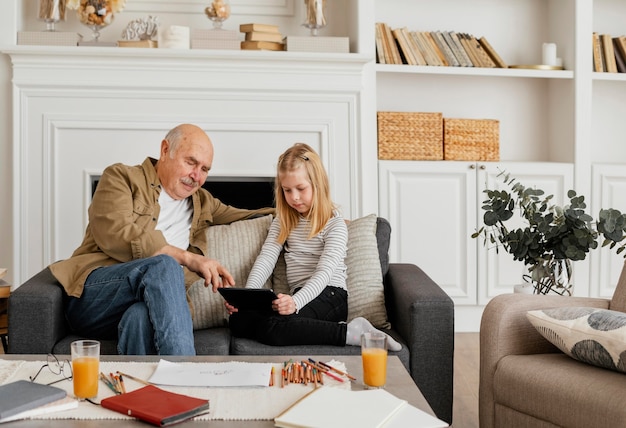 Abuelo y niña de tiro medio en sillón