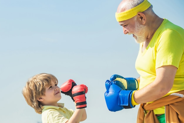 Abuelo y niño chico en postura de boxeo haciendo ejercicios con guantes de boxeo