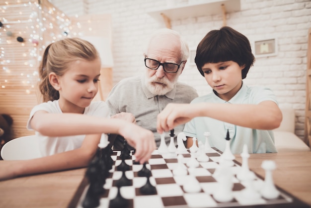 El abuelo y los niños juegan al ajedrez.