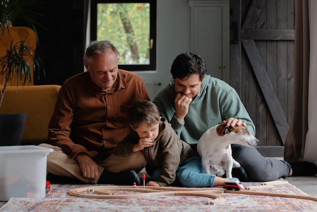 Foto abuelo y padre juega con un nieto en el piso en casa