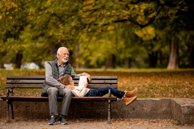 Abuelo pasando tiempo con su nieta en un banco en el parque el día de otoño