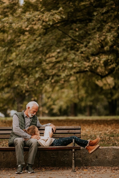 Abuelo pasando tiempo con su nieta en un banco en el parque el día de otoño