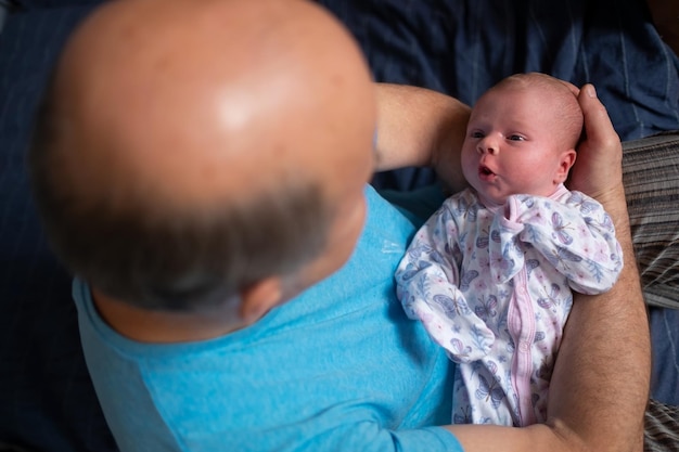 Abuelo sosteniendo a una hermosa niña recién nacida en casa