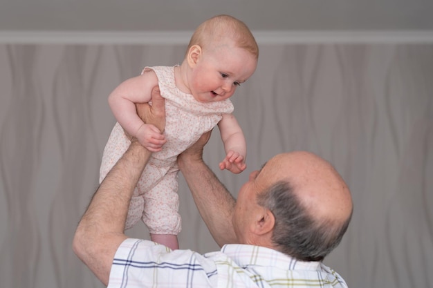 Abuelo sosteniendo a una niña caucásica de 8 meses