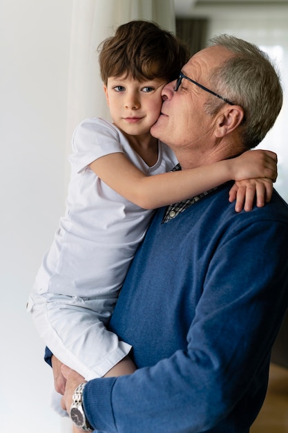 Foto abuelo sosteniendo a su nieto cerca de la ventana