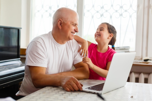 Abuelo y su nieta usando una laptop juntos.