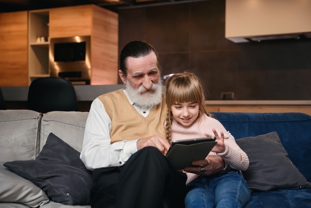 Abuelo con su nieta usando tableta en casa