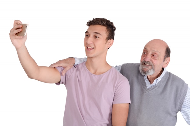 Abuelo y su nieto adolescente tomando un selfie.