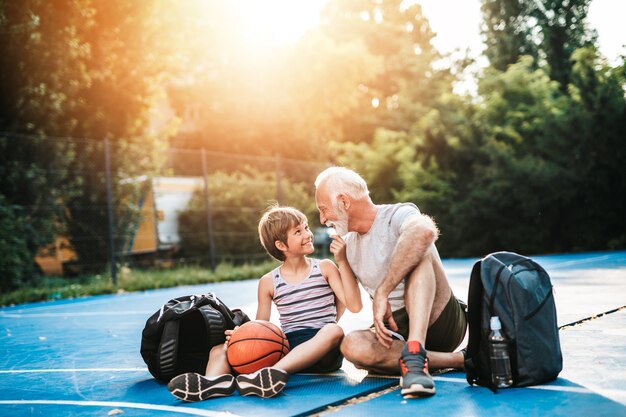 Abuelo y su nieto disfrutando juntos en la cancha de baloncesto.