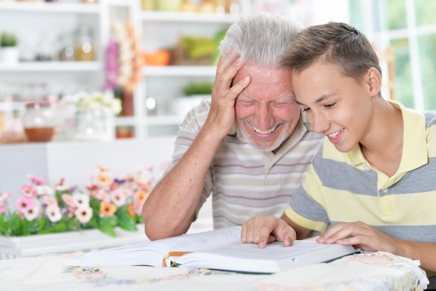 Abuelo y su nieto leyendo un libro en casa