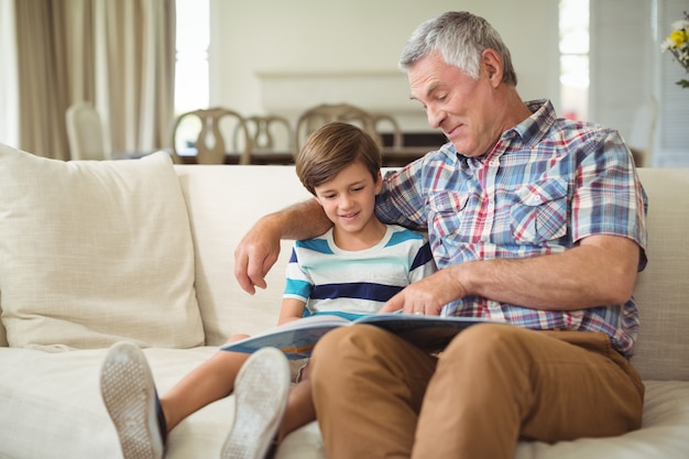 Abuelo con su nieto leyendo el libro en el sofá