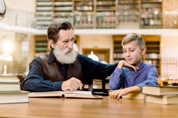 Abuelo, su nieto, maestro y alumno, sentado a la mesa en la antigua biblioteca.