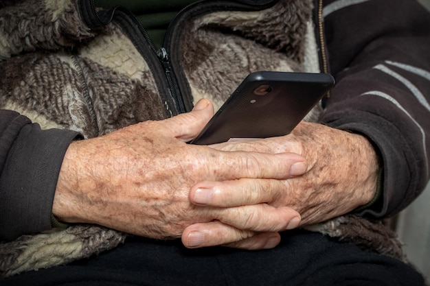 El abuelo tiene un teléfono móvil en sus manos Ocio para ancianos