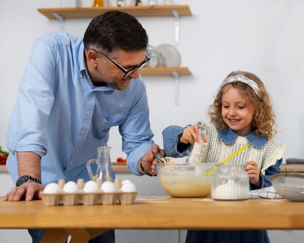 Foto abuelo de tiro medio y niña en la cocina.