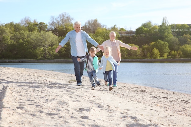 Abuelos felices jugando con niños pequeños en la orilla del río