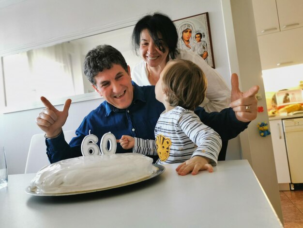 Foto los abuelos felices con el nieto disfrutando del pastel de cumpleaños en la mesa en casa