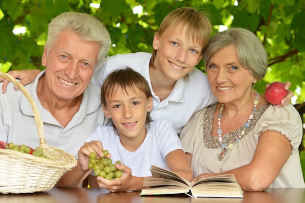 Abuelos con nietos leyendo en verano en la mesalectura en verano en la mesa