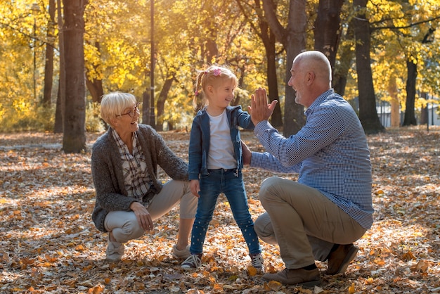 Abuelos y nietos sonrientes divirtiéndose juntos en el parque de otoño