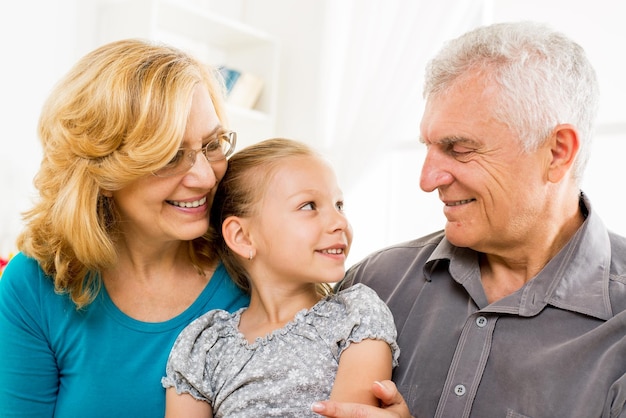 Abuelos con niña sentada en casa y disfrutando