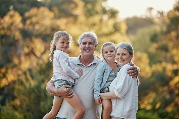 Abuelos niños y sonrisa en el parque al aire libre o en el patio trasero para unir amor y cuidado en la naturaleza Pareja mayor niñas y felicidad juntos para el retrato de vacaciones y el sol en Los Ángeles