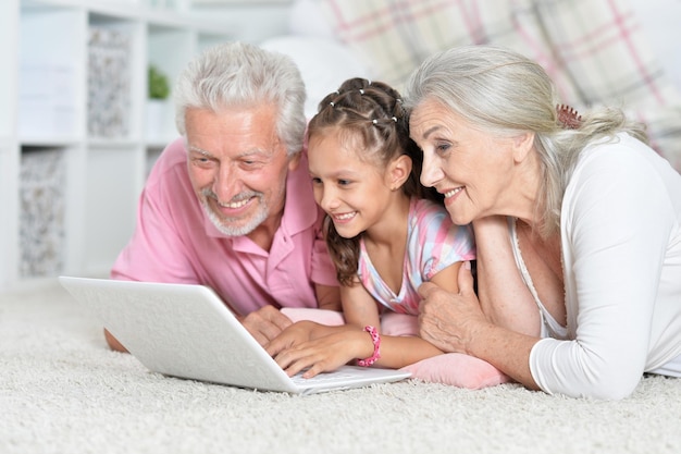 Abuelos con su nieta usando una laptop en casa