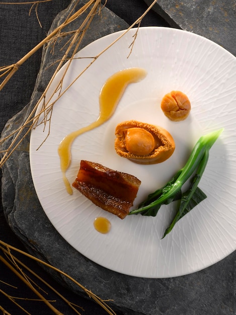 Abulón entero estofado con conpoy y fauces de pescado en salsa marrón servido en un plato aislado en la vista superior de la mesa de la comida