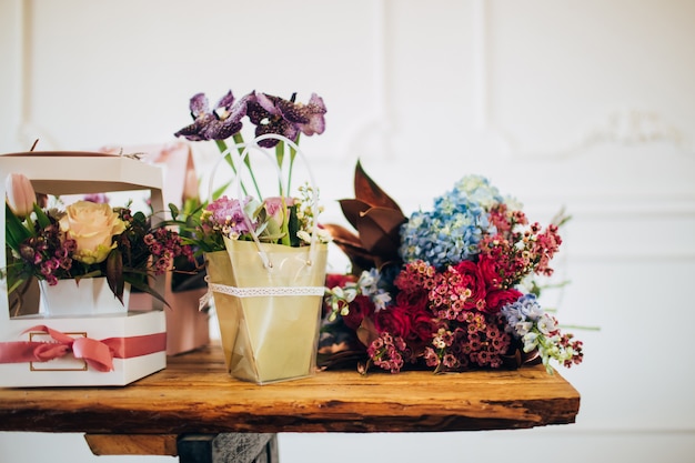Abundancia de flores. cajas de flores se colocan sobre una mesa de madera. tienda de flores. mostrador en la florería.