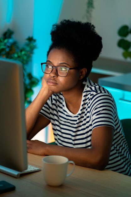 Aburrida mujer afroamericana freelance se sienta en la oficina de casa pensando en el proyecto mirando el escritorio