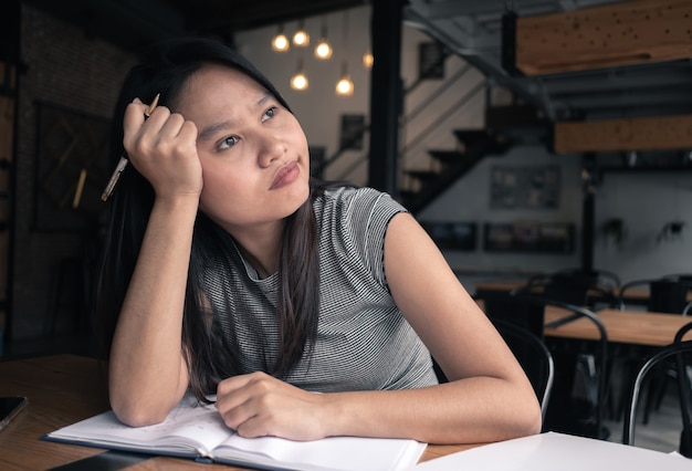 Aburrida mujer pensando en proyecto en cafetería