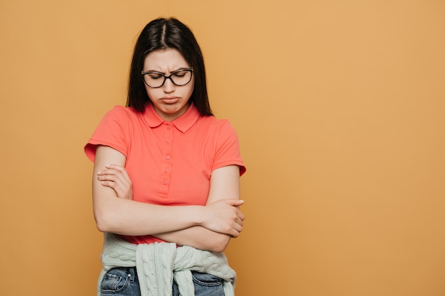 Aburrida niña con gafas, vestida con una camiseta rosa, cansada