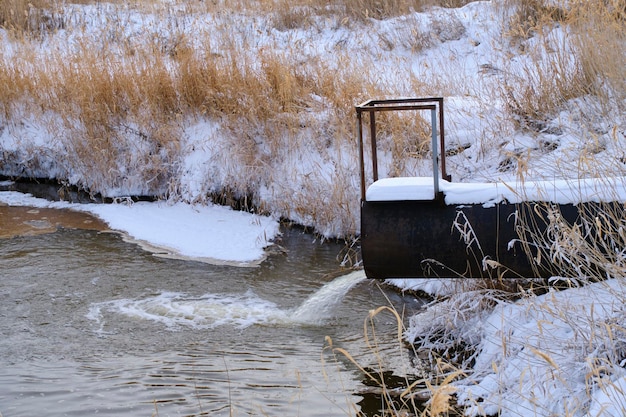 Abwassereinleitung aus dem Rohr in den Fluss im Winter Flussverschmutzung und Ökologie