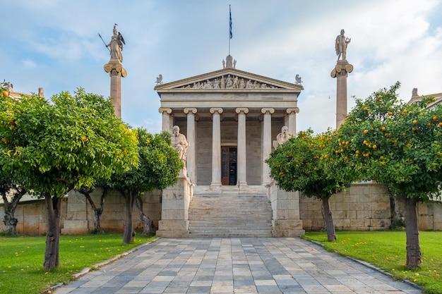 Foto academia de atenas com colunas de mármore com esculturas de apolo e atenas e árvores de tangerina dentro