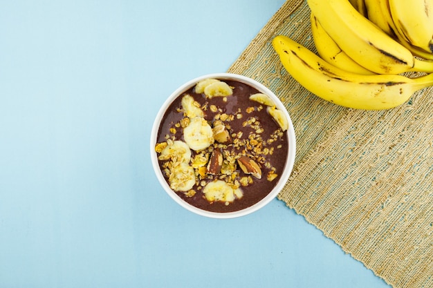 Açaí brasileiro em uma tigela branca com banana, granola e castanhas.