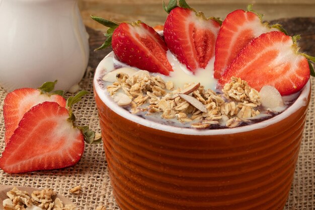 Açaí congelado com granola de morango e leite condensado em uma tigela Foco seletivo