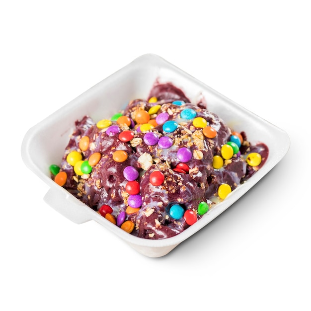 Açaí congelado com granola e coberturas coloridas em uma lancheira de isopor no fundo branco