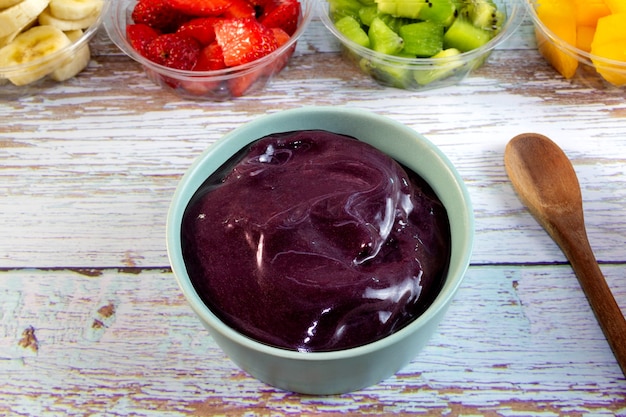 Acai-Schale auf einem Holztisch Frisches Obst im Hintergrund