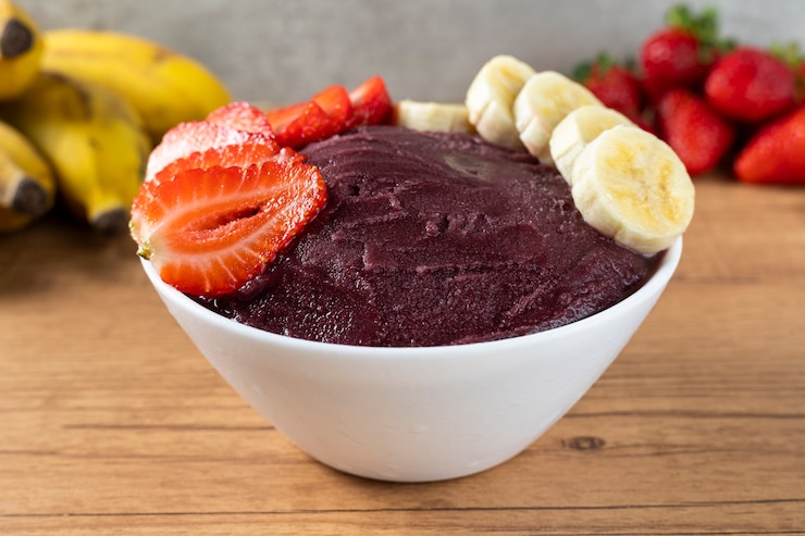 Foto açaí, tigela de sorvete de açaí congelado brasileiro com morango e banana. com frutas na mesa de madeira. vista frontal do menu de verão