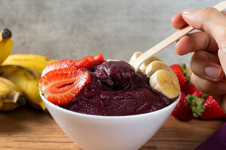 Foto açaí, tigela de sorvete de açaí congelado brasileiro com morango e banana. com frutas na mesa de madeira. vista frontal do menu de verão
