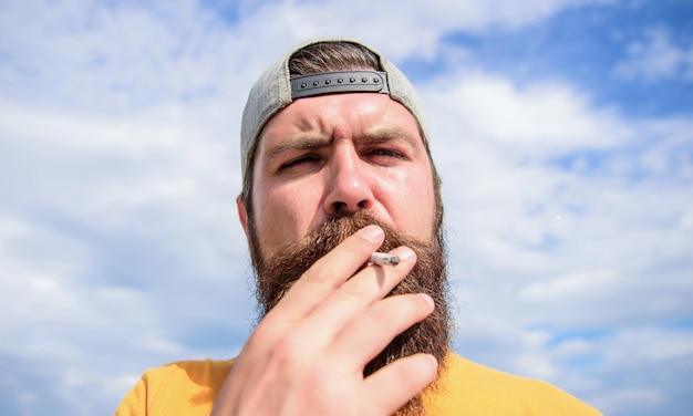 Acalme-se Conceito de hábito de fumar Hipster pensativo rosto concentrado com fumaça voando para fora da boca Fumar ao ar livre Homem barba e bigode fumando fundo do céu Efeito relaxante de fumar