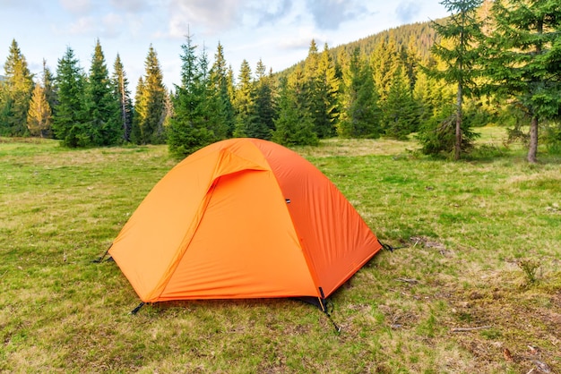 Acampamento de barraca laranja na floresta verde