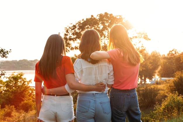 Acampamento de verão aulas de verão amigos universidade três amigas alegres dançam e pulam no verão