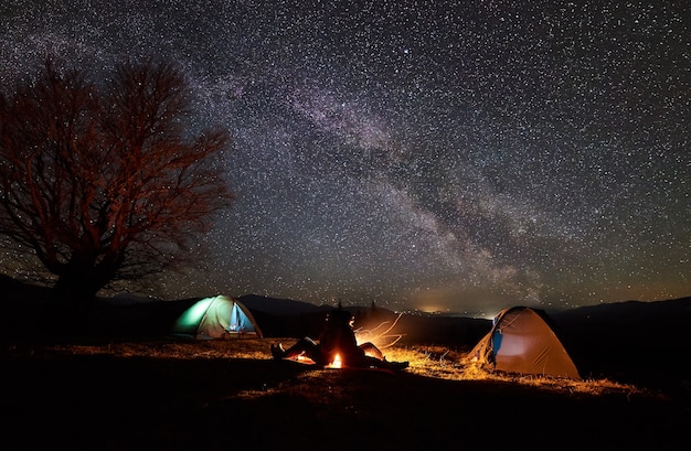 Acampamento noturno. caminhantes descansando perto da fogueira sob o céu estrelado