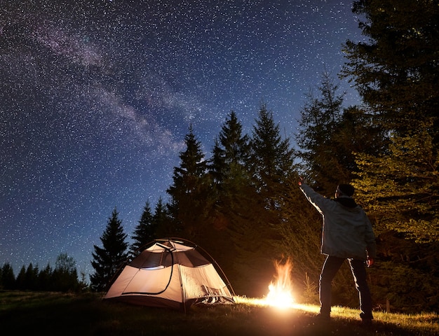 Acampamento noturno nas montanhas sob o céu estrelado e a via láctea