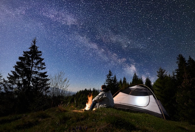 Acampamento noturno nas montanhas sob o céu estrelado e a Via Láctea