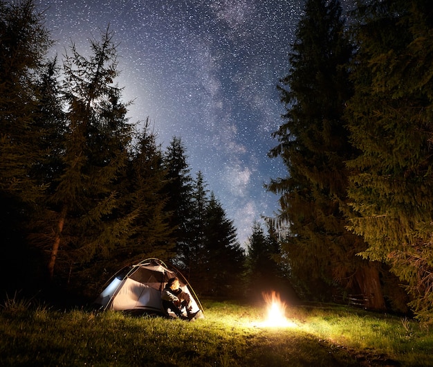 Acampamento noturno nas montanhas sob o céu estrelado e a Via Láctea