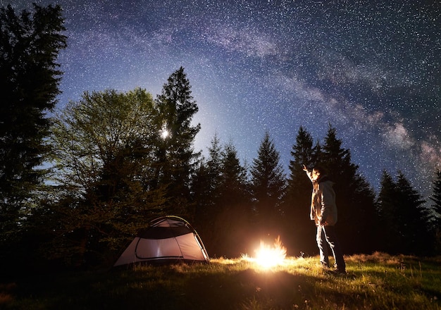 Acampamento noturno nas montanhas sob o céu estrelado e a via láctea