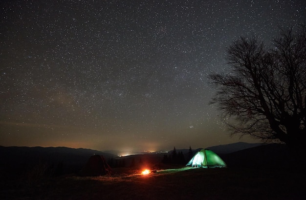 Acampamento noturno no vale da montanha sob o céu estrelado