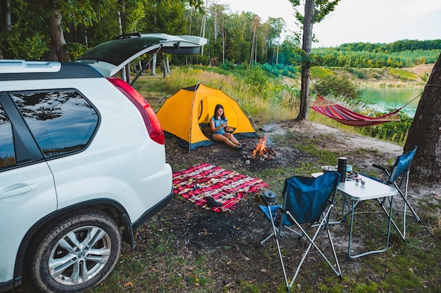 acampamento perto do lago mulher sentada em tenda amarela carro SUV branco