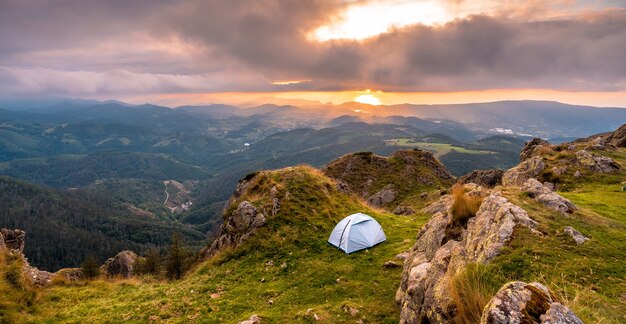 Acampamento selvagem no topo de uma montanha ao pôr do sol, dormindo ao ar livre após a longa caminhada nas montanhas