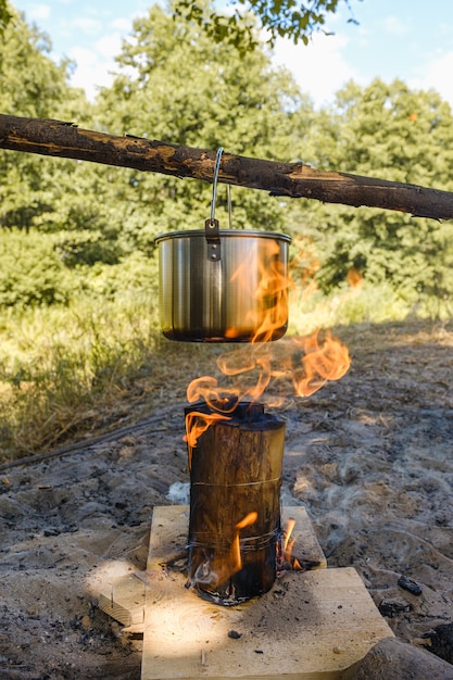 Acampando, uma panela com água ferve sobre o fogo.